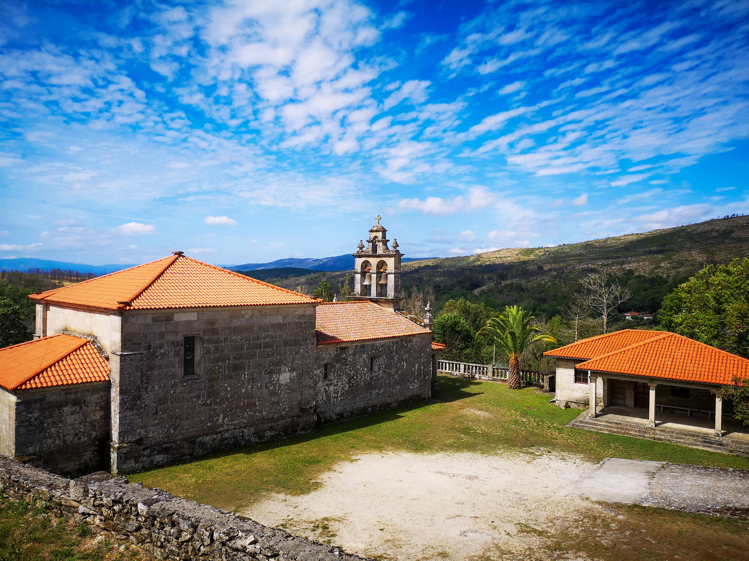 Stone church and grounds under blue sky in the rolling spanish hills Camino Sanabres Spain