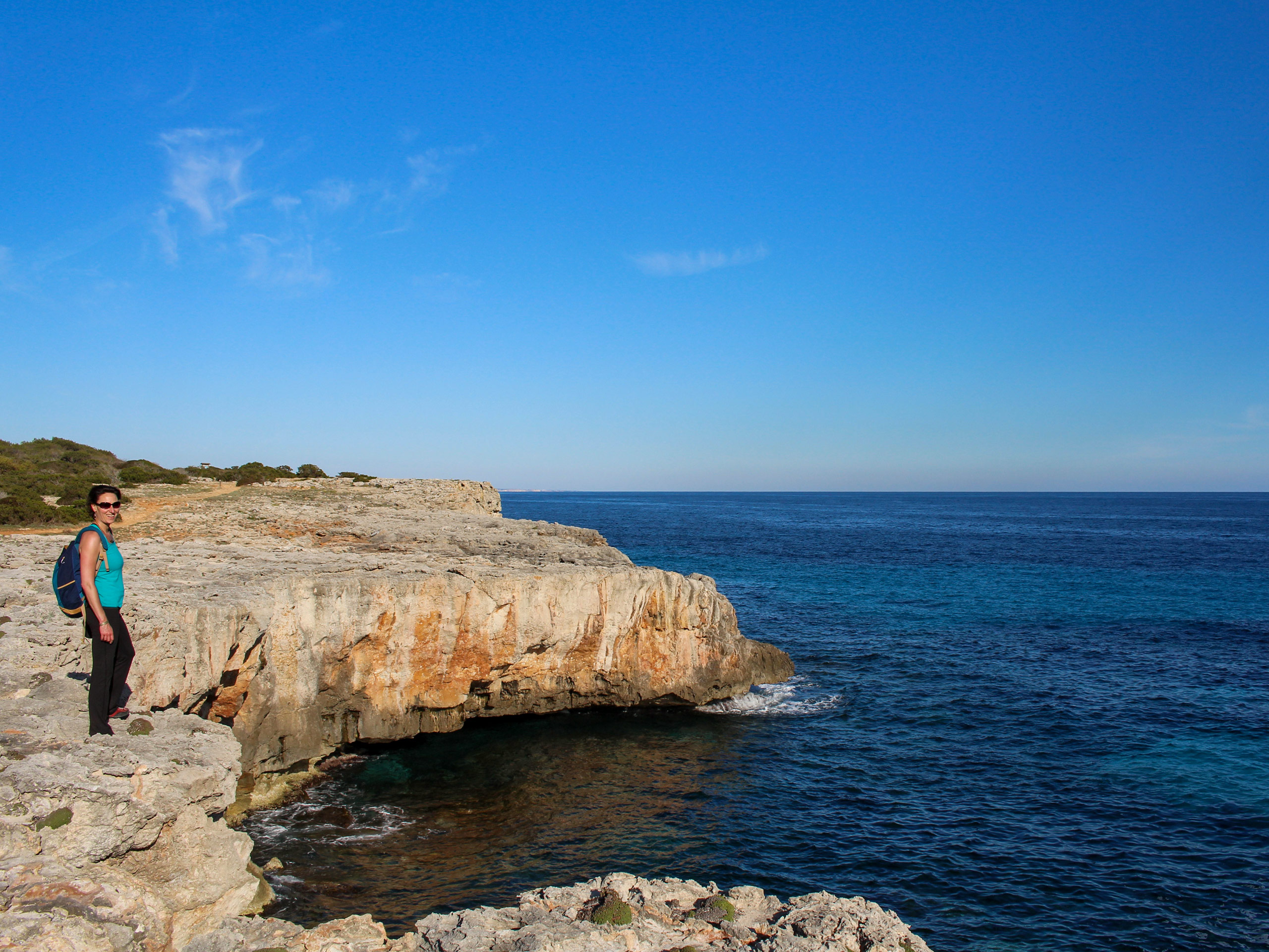 Hiker standing on rock shores of the ocean mediterranean sea walking tour Menorca Spain