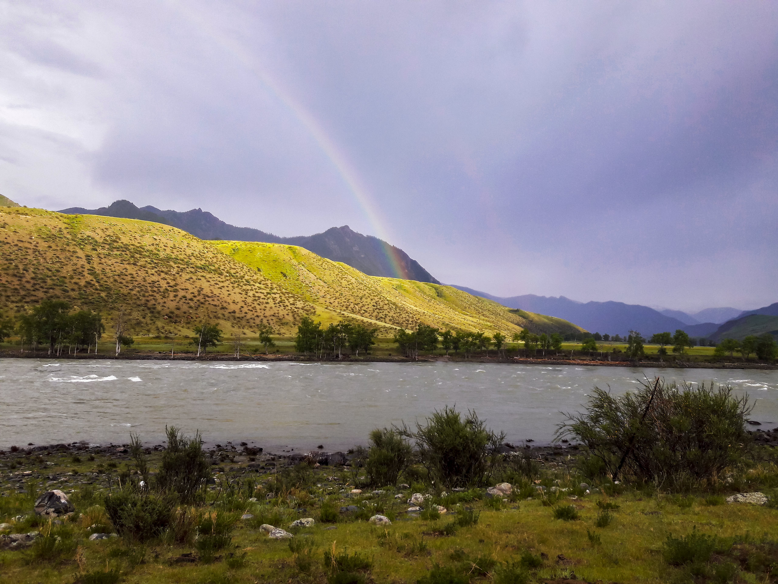 Rainbow over mountain hills and river exploring Altai mountians Russia