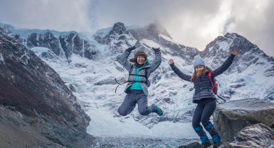 Two girls posing in front of a massive glacier on W Trek