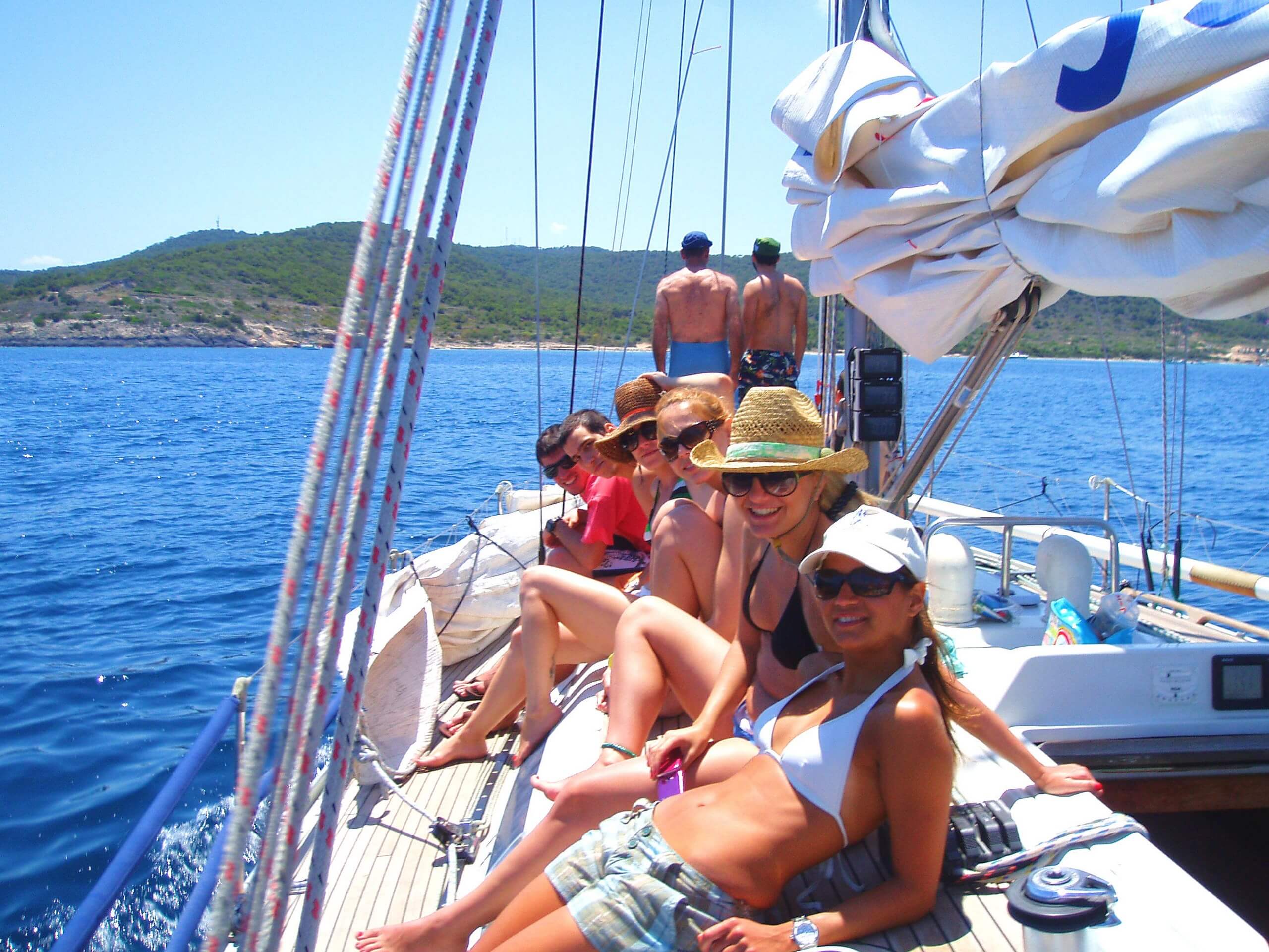 Group of friends posing on a yacht deck while on sailing adventure