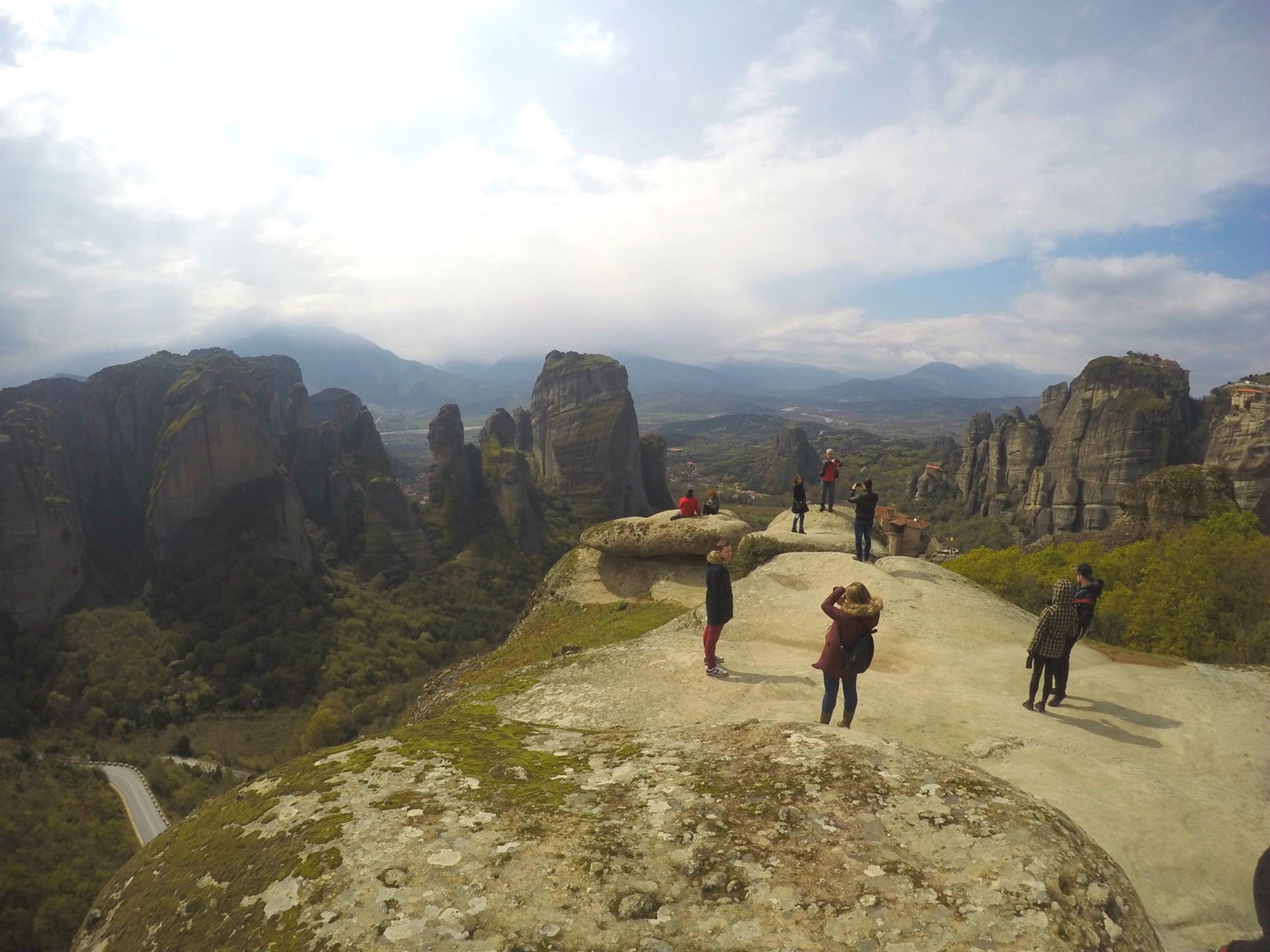 Group of tourists on a rock formation, observing the Meteora views in Greece