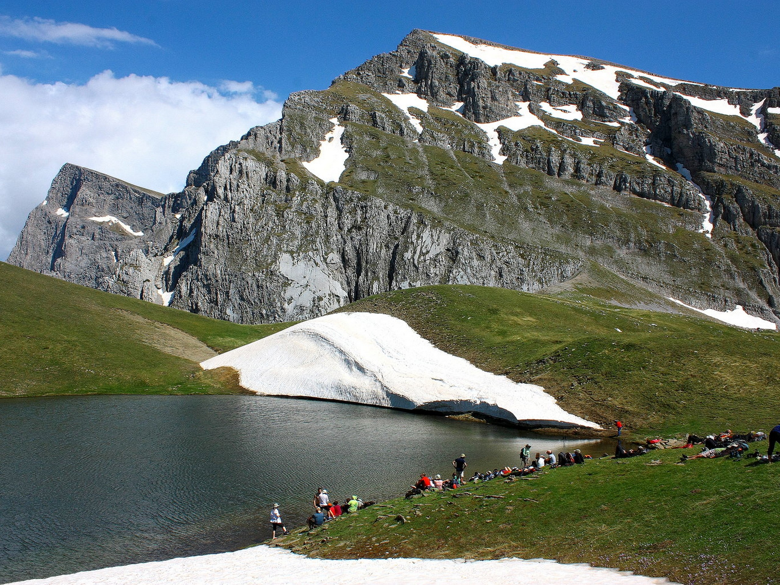Big group of adventurers having a break near the lake in Greek mountains