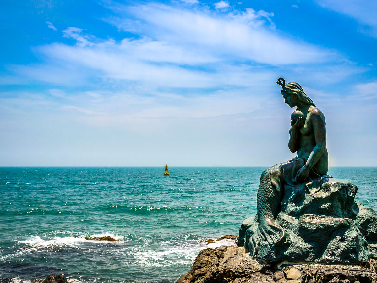 Haeundae beach mermaid statue South Korea ocean coast adventure bike tour