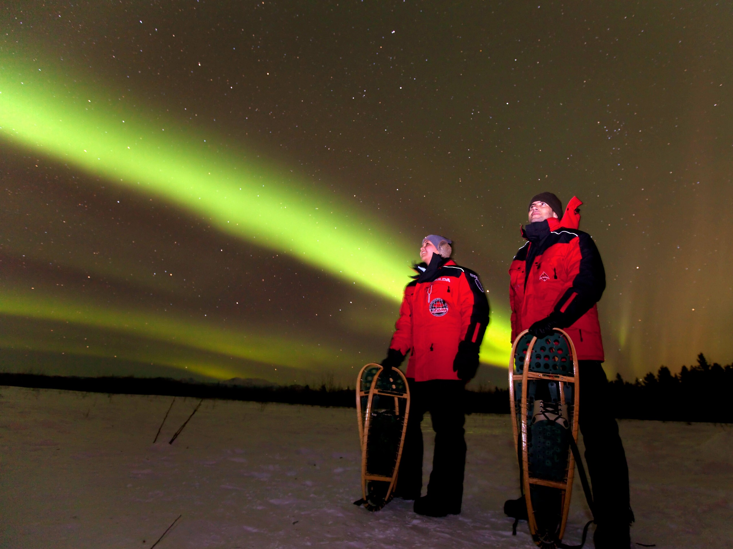 Couple watching the Northern Lights while on a snowshoeing trip