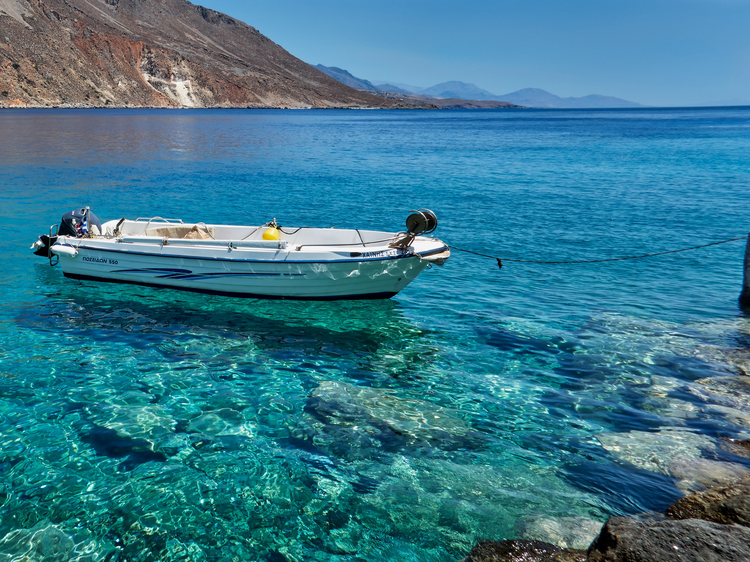 White boat floating in the waters of Crete