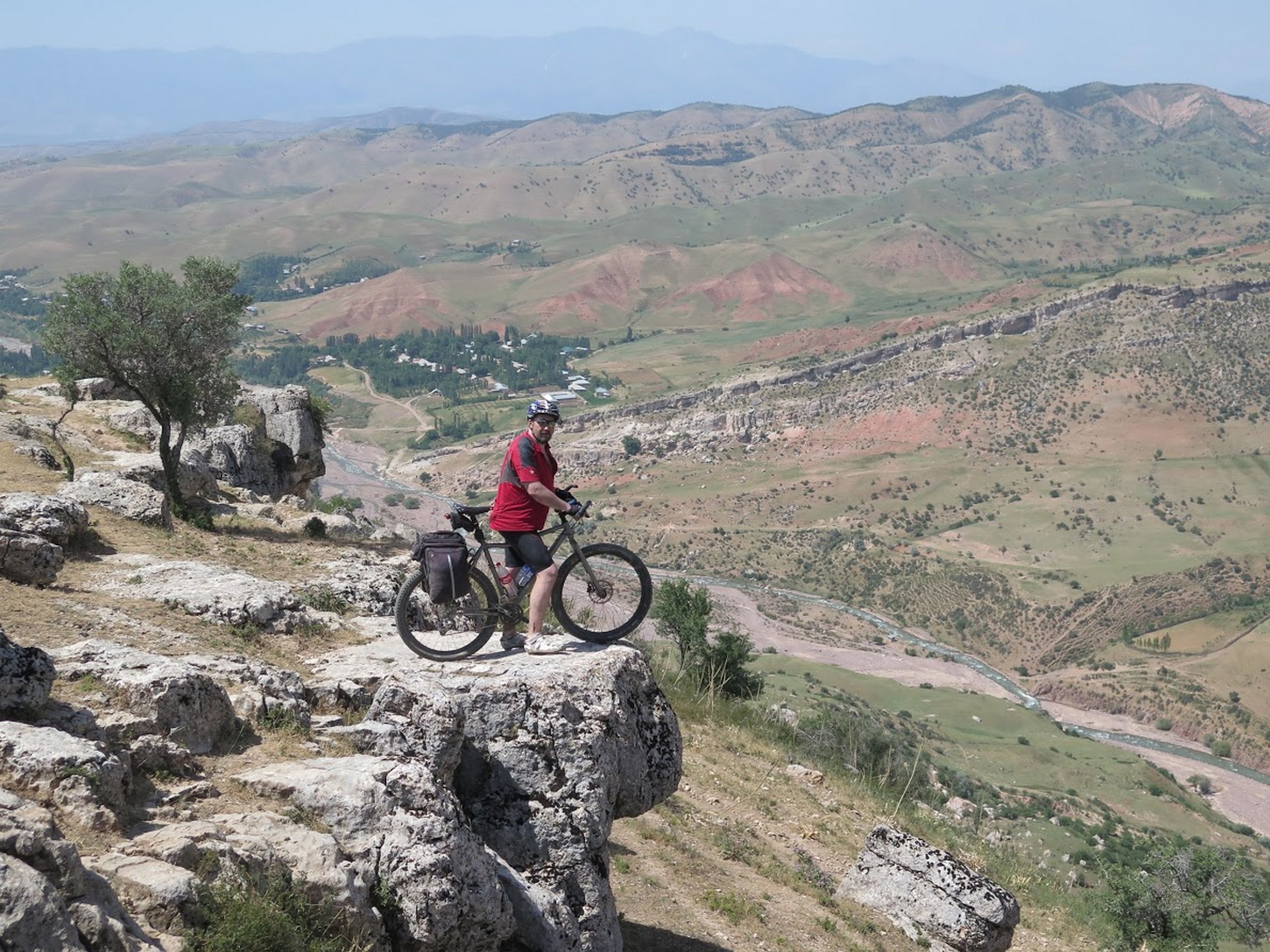 Cyclist standing on the rock cliff in Uzbekistan