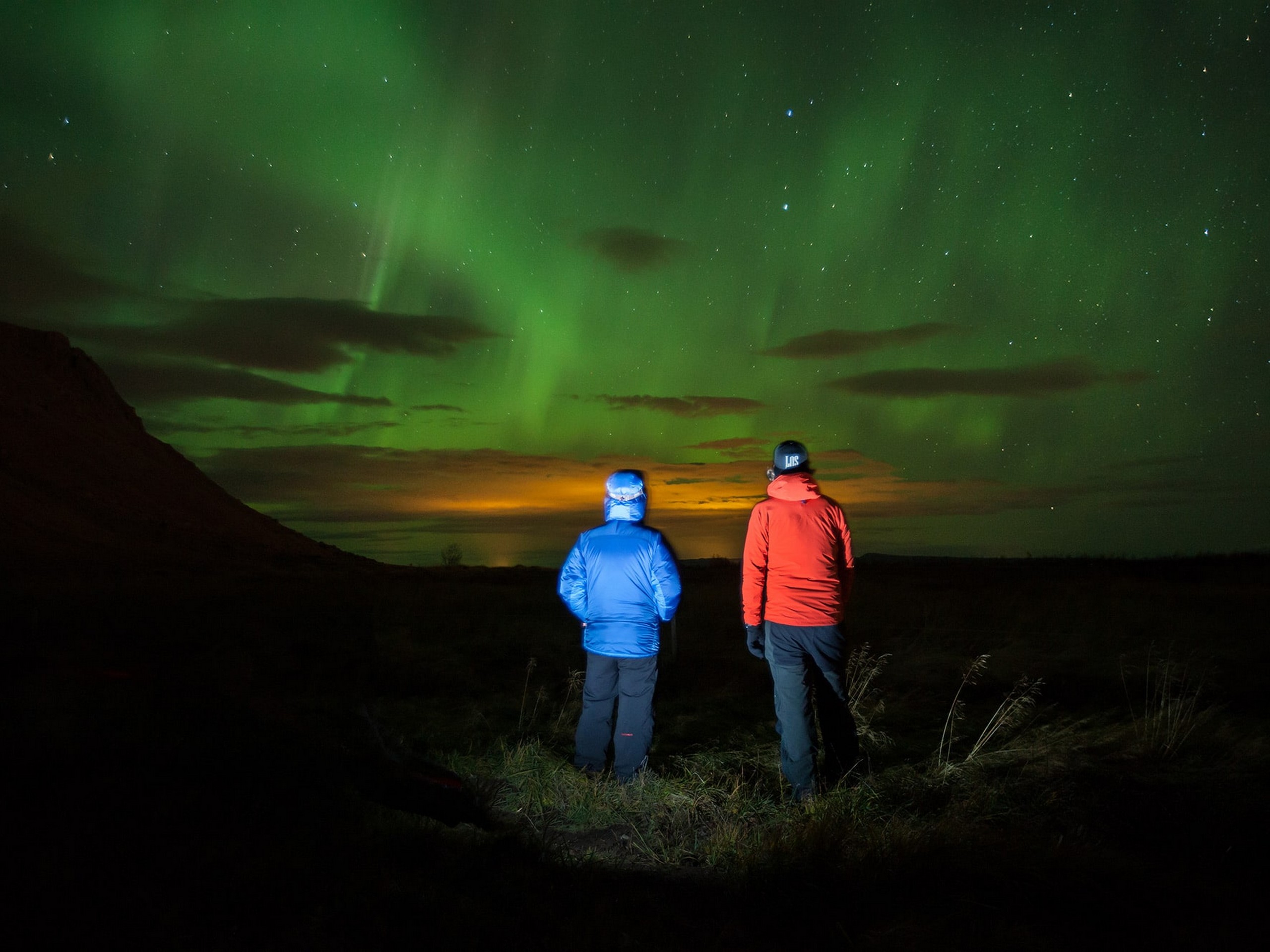 Couple enjoying the Northern Lights while on a guided tour in Iceland - Photo by Bjorgvin Hilmarsson