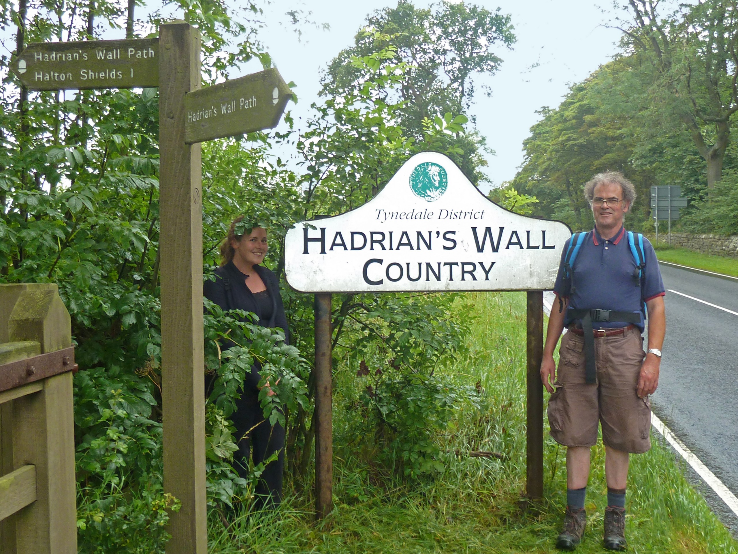 Two hikers posing near the roadsign