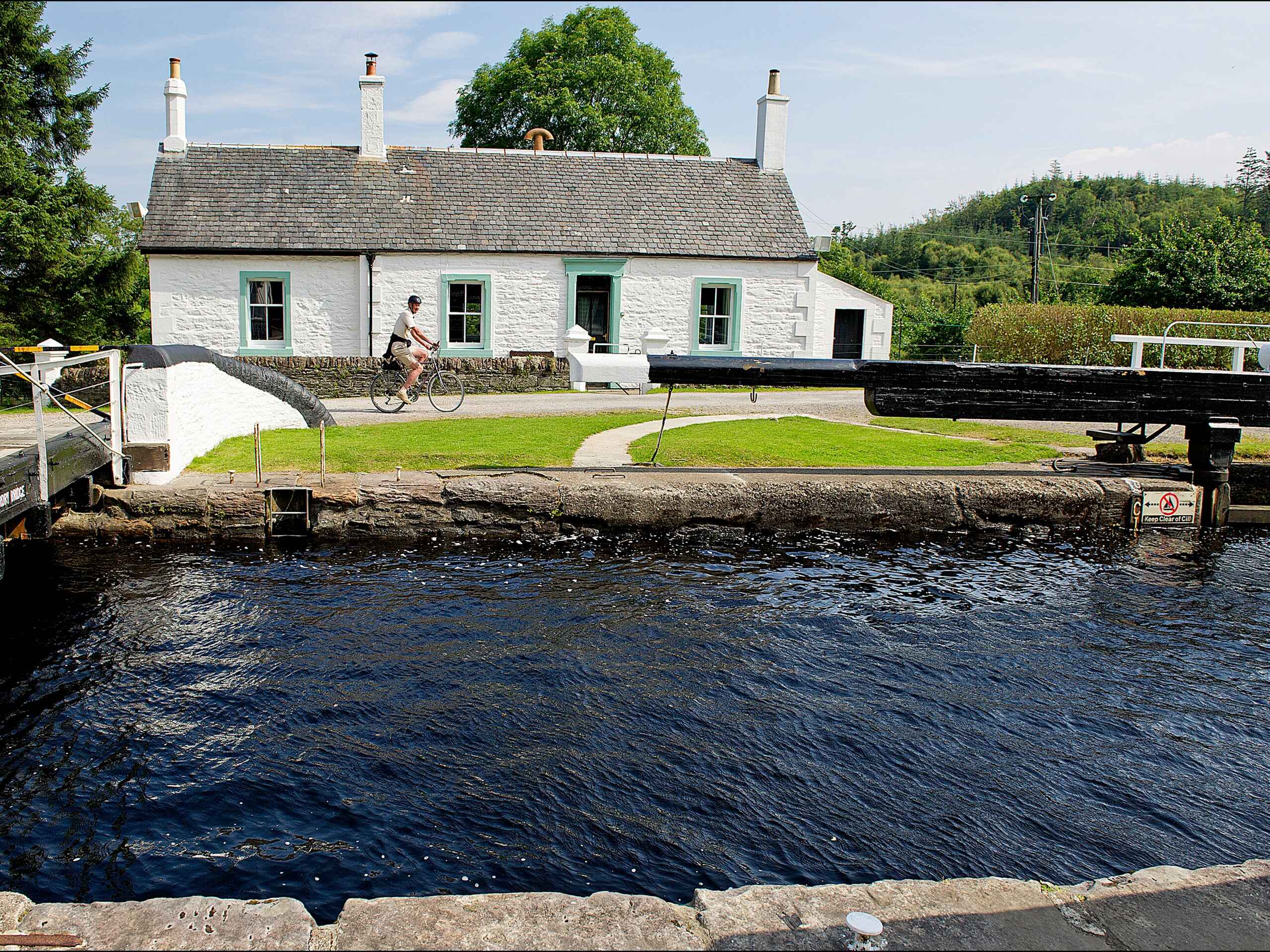 Cyclist passing Bannatyne Canalside Cottage on the Crinan Canal c Peter Sandground