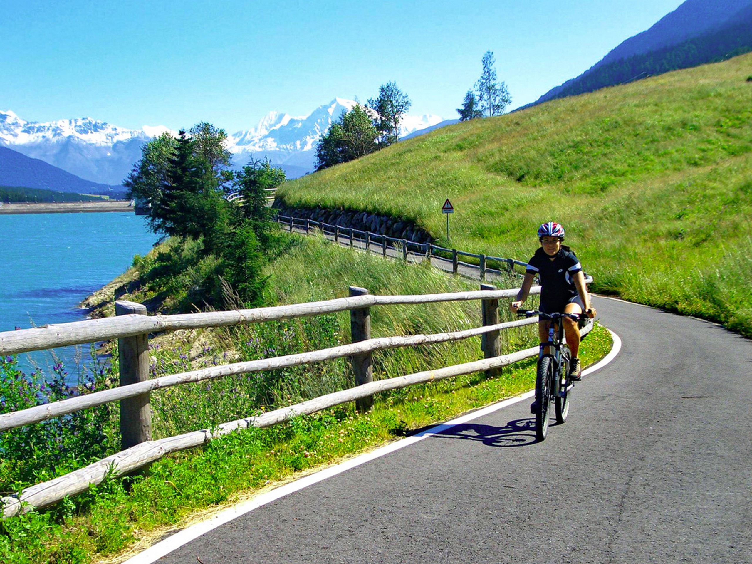 Biker cycling along the Etsch river (Adite) in Italy