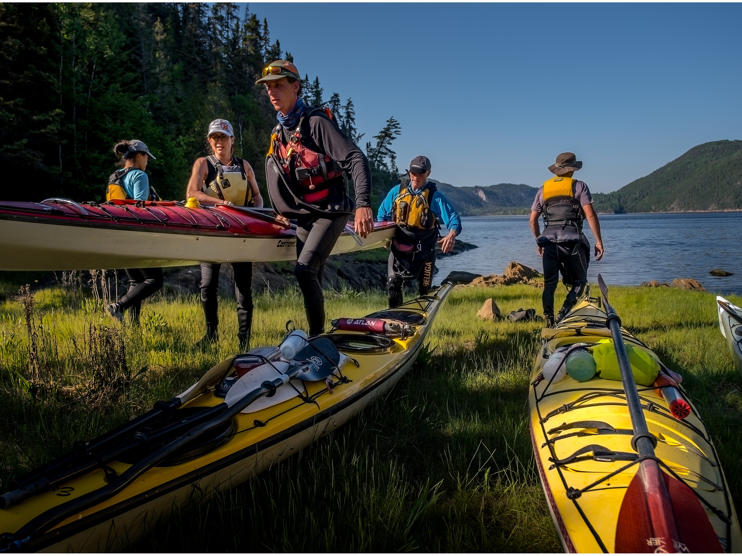 Group of kayakers standing near their kayaks in Quebec