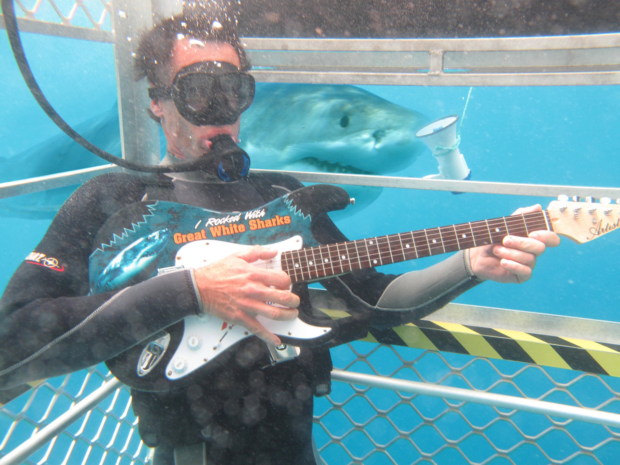 Posing with an electric guitar while shark cage diving