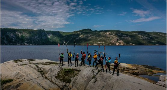 Group of Kayakers posing on a rock near the Fjord